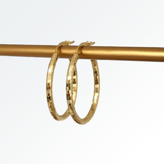 A pair of 14k gold diamond cut oval hoop earrings hanging from a gold-colored hook.