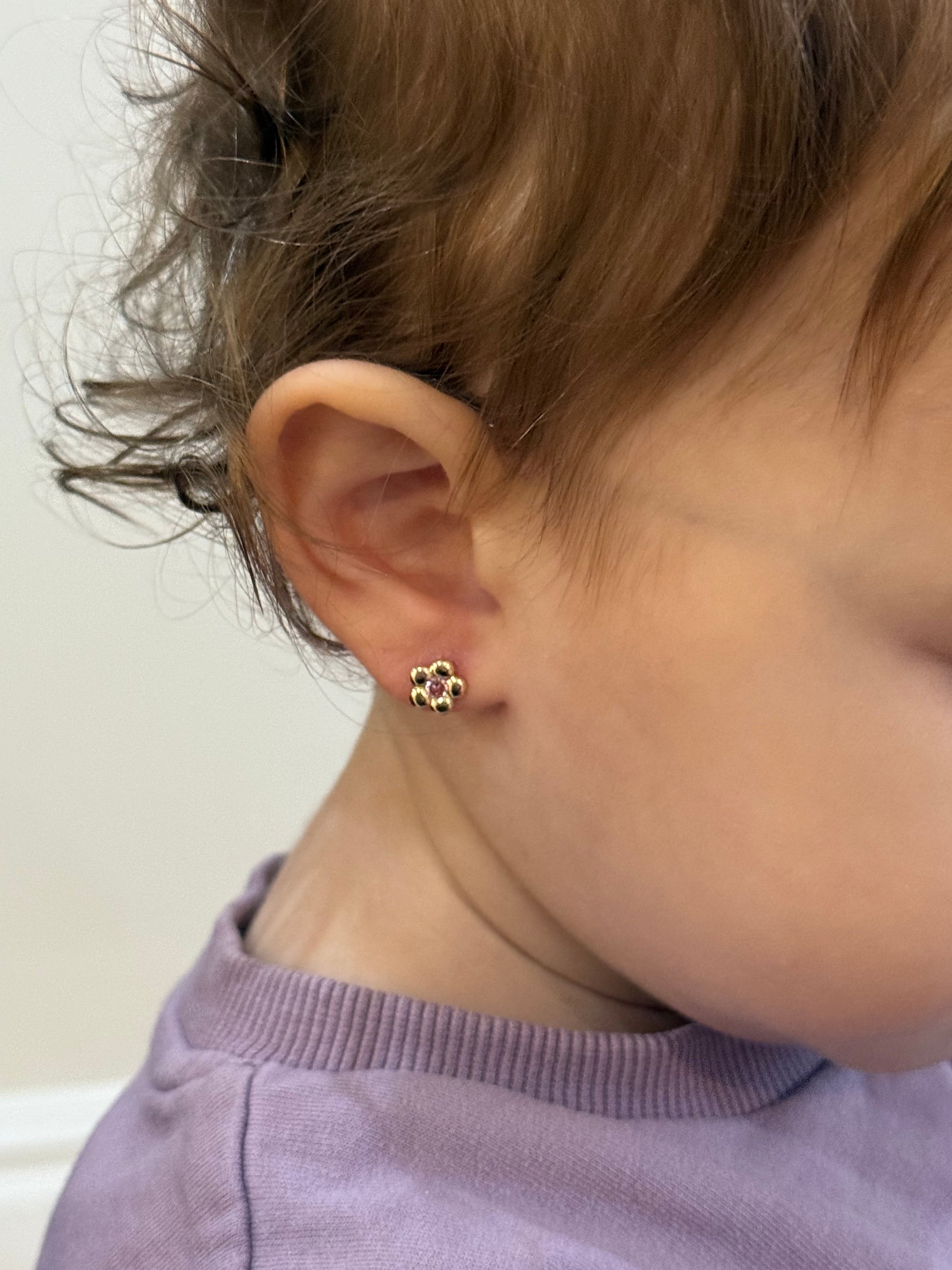 Child wearing 14K gold flower screw back earrings safe for sensitive ears