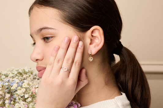 Model wearing 14K two tone gold heart drop huggie earrings.