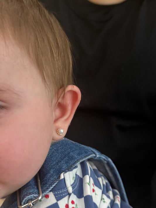 Close-up of a child wearing a small earring with a dark background